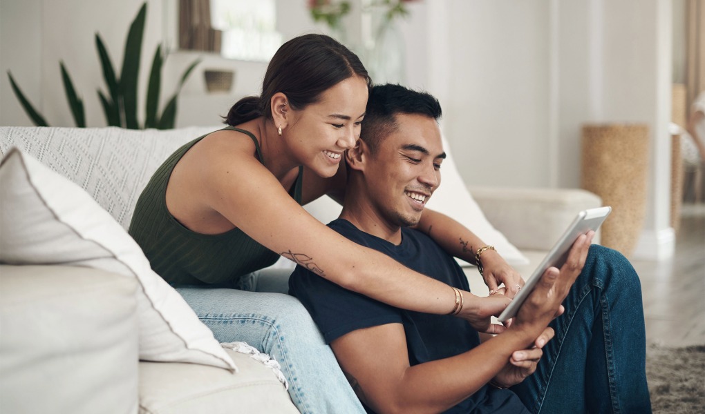 Happy couple looking at My Insurance Manager online portal for viewing and updating AMP home and car insurance policies.